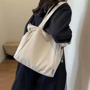 Detailed side view of off-white canvas tote bag with drawstring fold design and brand tag