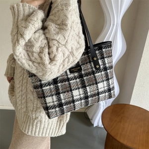 Detail of checkered woven tote bag with leather handles and gold rivet accents