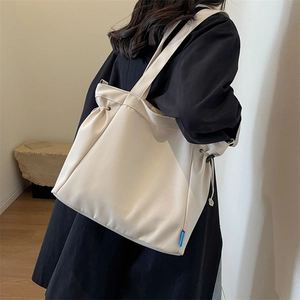 Minimalist beige canvas crossbody tote bag with adjustable drawstring side detail