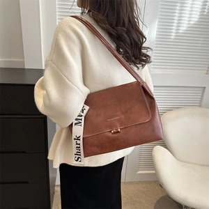 Detail view of brown vintage leather crossbody bag with broad fabric shoulder strap decoration