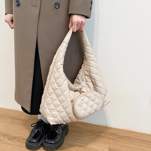 Detailed view of beige quilted faux leather crossbody bag featuring a round coin purse accessory