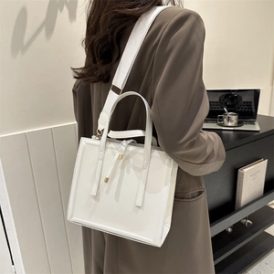 White minimalist square tote bag with wide strap and sleek handle on a female model