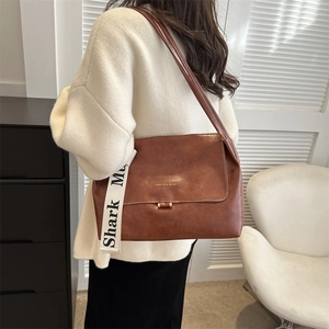 Close-up of brown vintage faux leather shoulder bag with wide shark mu printed strap