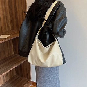 Close-up of minimalist cream white pebbled leather hobo bag with wide adjustable strap