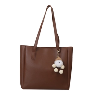 Minimalist dark brown PU leather tote bag with white plush charm on white background