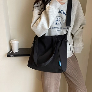 Detail of minimalist black canvas tote bag with adjustable strap and side drawstring