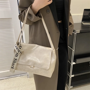 Detail of a beige matte leather crossbody bag featuring a branded Shark strap and gold buckle