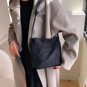 Detail of the embossed onwards and upwards text on the black suede shoulder bag