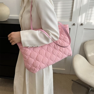 Détail d'un cabas rose matelassé avec motif à losanges et bandoulière porté par un mannequin