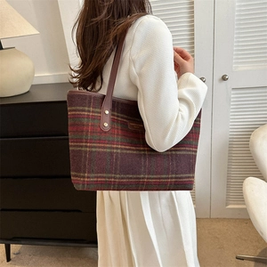 Detail of wool plaid tote bag with brown leather shoulder strap shown on a model