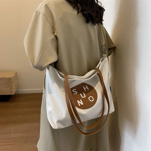 Minimalist canvas tote bag with brown leather handles and brand patch for women