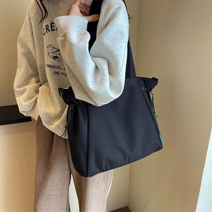 Side view of large black canvas drawstring tote bag shown on a model for daily use