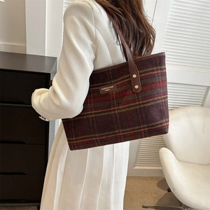 Detail of vintage plaid tote bag featuring leather handle and metallic brand logo