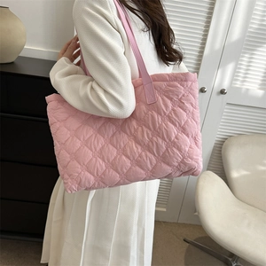 Vue latérale d'un grand sac cabas rose en nylon matelassé porté à l'épaule pour femme