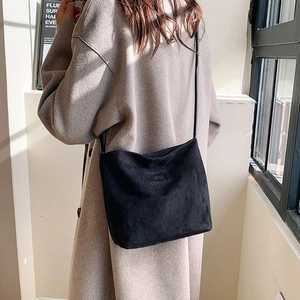 Minimalist black faux suede crossbody bag with printed slogan shown on female model