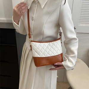 Detail view of retro crossbody bag with beige quilted pattern and brown leather base