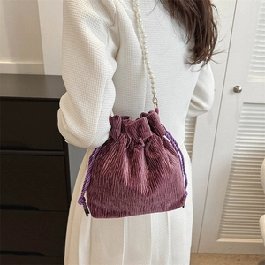 Detail of purple corduroy drawstring bucket bag with elegant pearl decorative strap
