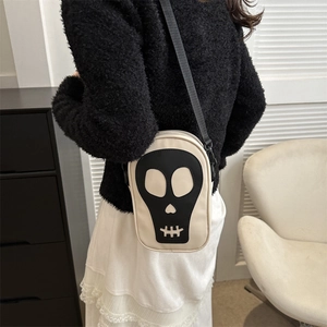 Détail d'un sac bandoulière minimaliste avec écusson tête de mort et large sangle sur mannequin