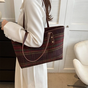Detail of wool blend plaid tote bag with dark brown leather straps and gold metal rivets