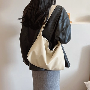 Chic cream white faux leather hobo bag with wide strap shown on model's shoulder