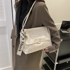 Detail of cream flap shoulder bag with textured faux leather and silk scarf handle
