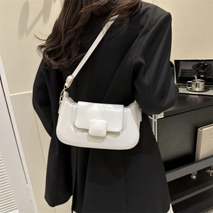 Minimalist white PU leather crossbody baguette bag worn over a black blazer for a stylish look