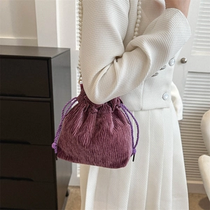 Detail of purple corduroy drawstring bucket bag with elegant white pearl strap handle