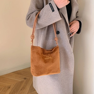 Minimalist brown suede shoulder bag with embroidered text and knotted strap detail