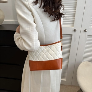 Detail of crossbody bag featuring cream quilted leather and brown contrast panels