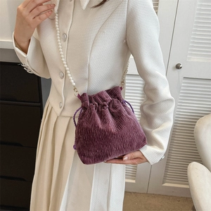 Detailed shot of purple corduroy bucket bag with elegant pearl strap and drawstring closure