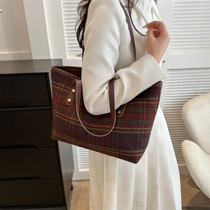 Detail of wool plaid tote bag featuring vintage pattern with brown leather handles and rivets