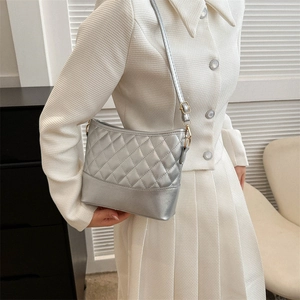 Detail of silver quilted crossbody bag with rhombic texture and gold metallic buckle