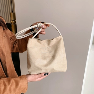 Detail of suede shoulder bag featuring onwards and upwards embroidery and knotted strap