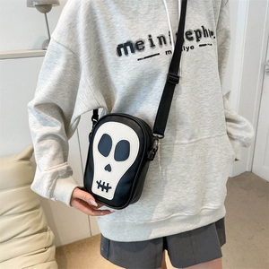 Détail d'un sac bandoulière noir avec patch tête de mort blanche et sangle réglable