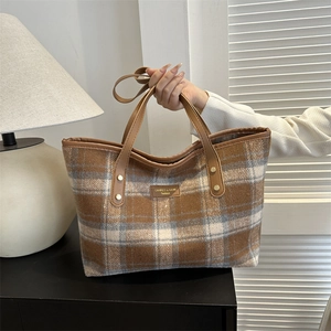 Detailed macro view of the plaid wool tote bag featuring premium leather handles and golden rivets