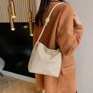 Minimalist beige suede shoulder bag with 'onwards and upwards' embroidery and knotted strap