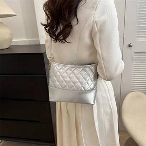 Detail of silver metallic quilted crossbody bag with sleek mirror finish and gold hardware