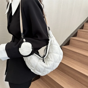 Detail of white quilted crescent bag with matching mini pouch charm and zipper