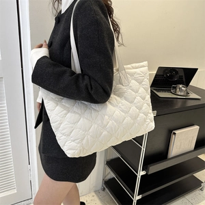Détail du sac cabas matelassé blanc présentant une texture en losanges et de longues bretelles