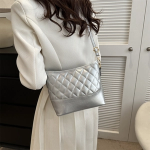 Silver quilted crossbody bag with gold metallic buckle and adjustable strap on a model