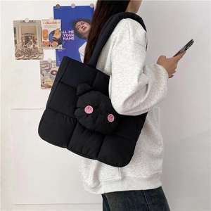 Detail of black quilted puffer tote bag with a cute cartoon bear pocket and plush texture