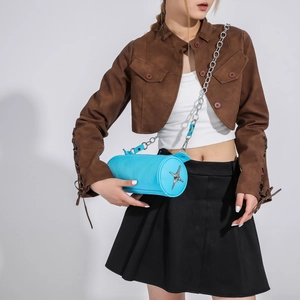 Detail of bright blue cylinder crossbody bag with silver star and metal chain on model