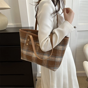 Detailed close-up of brown checkered tote bag with premium leather straps and logo badge