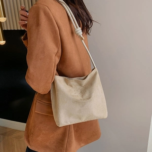 Detail view of suede crossbody bag with onwards and upwards white embroidery