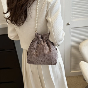 Detail of pleated drawstring bucket bag with pearl strap and smooth brown satin fabric
