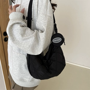 Detail of black quilted half-moon nylon crossbody bag with small round coin purse charm