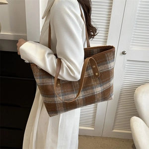 Detail of premium plaid wool tote bag with reinforced leather handles and metal rivets