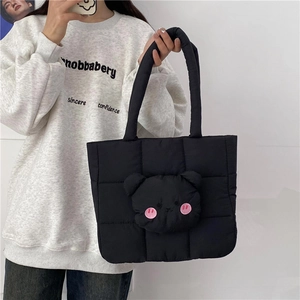 Detail of black quilted nylon tote bag featuring a cute 3D plush bear head decoration