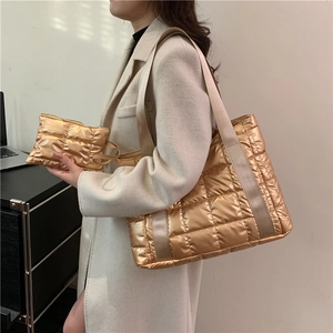 Detail of golden quilted tote bag and matching pouch showing metallic finish texture