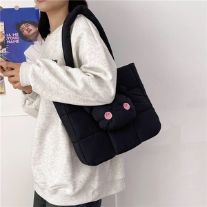 Detail of a black quilted nylon crossbody bag featuring a cute cat doll charm
